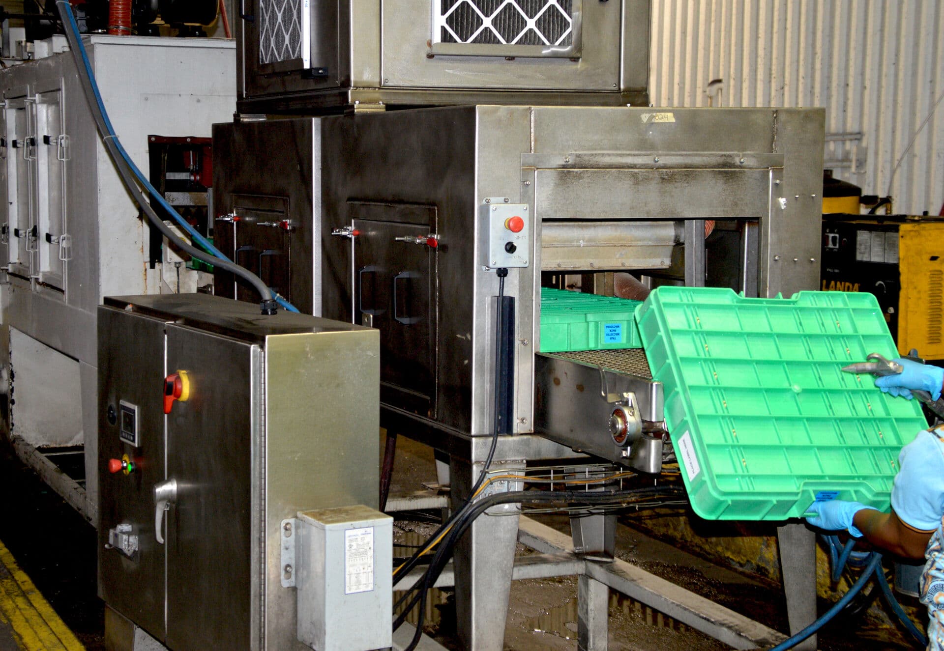 Green plastic dunnage exiting an industrial dunnage washing system